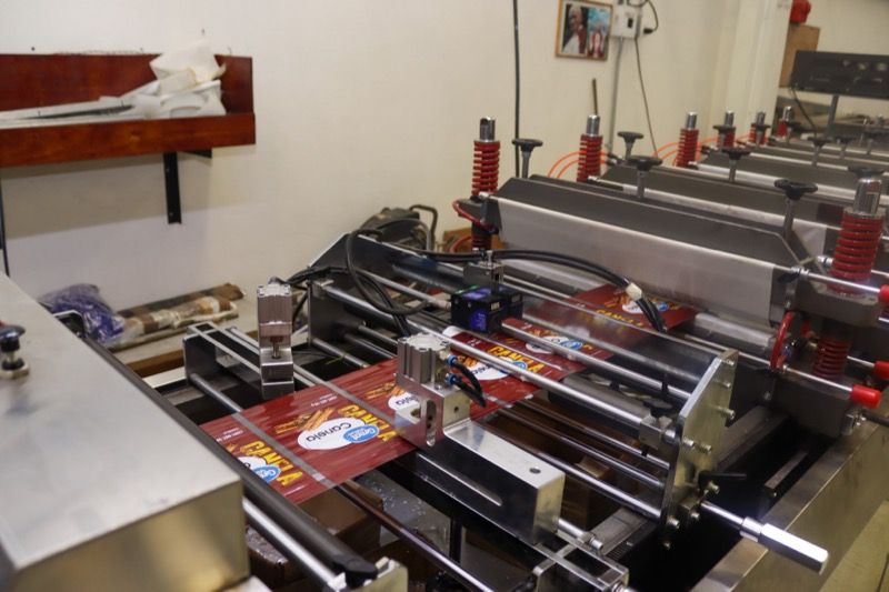 Bolsas impresas para tostadas saliendo de la máquina bolseadora