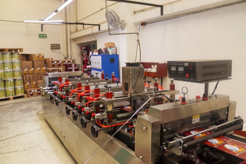Línea de máquinas bolseadoras en la planta, con cajas de producto terminado al fondo