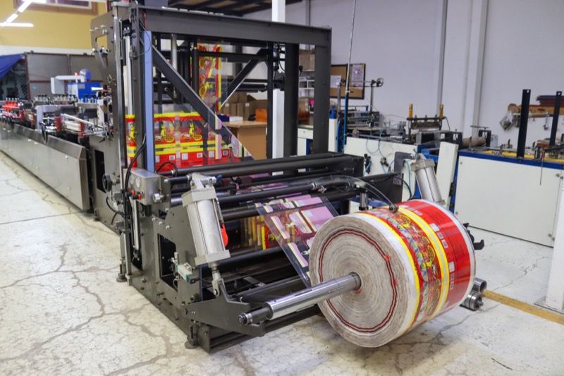 Máquina bolseadora en la planta de Falitopack con una bobina impresa en rojo y amarillo montada en el desbobinador